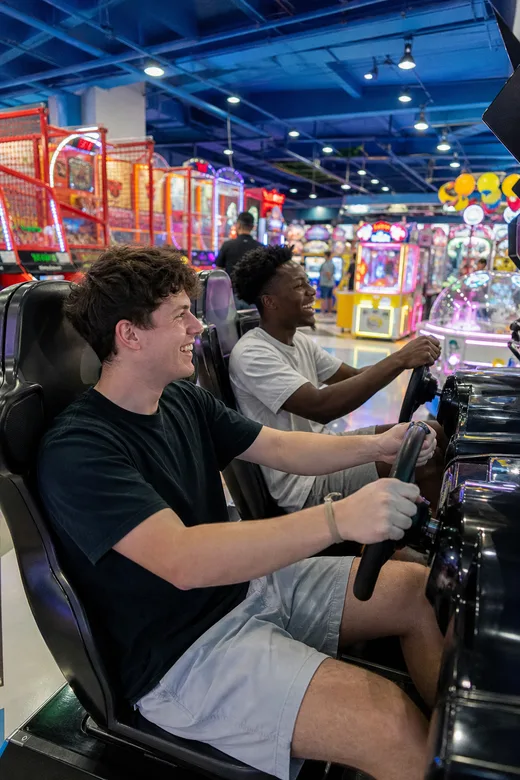 Friends racing in arcade driving cabinets